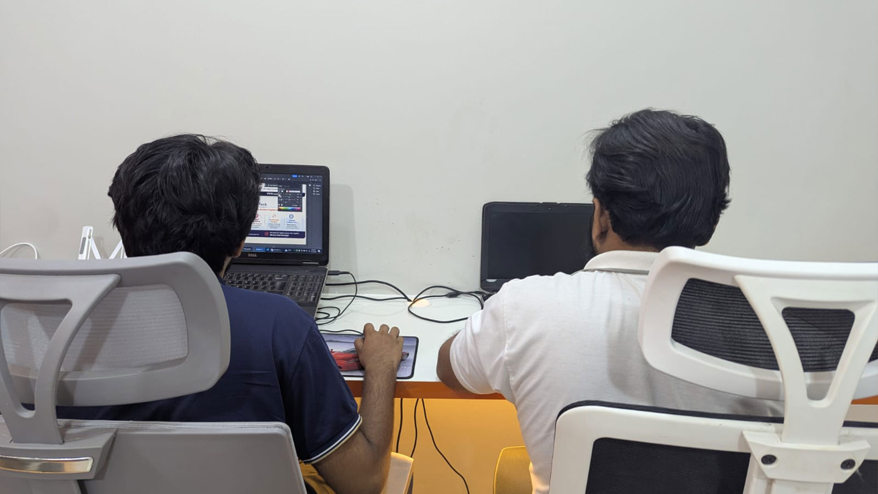 Web developers working on laptop computers in a modern IT office workspace