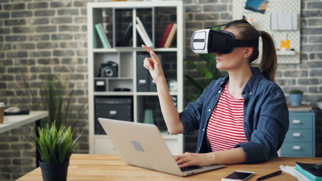 Woman wearing a virtual reality VR headset interacting with digital UI elements in an office environment
