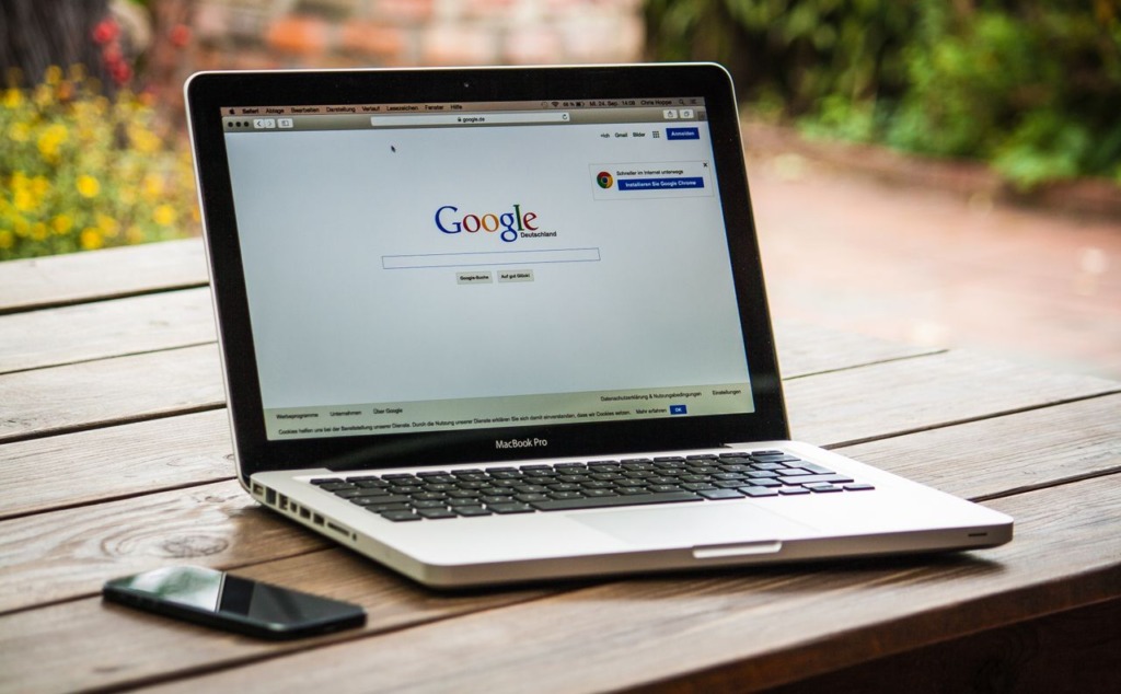 Open laptop displaying the Google Search homepage setup on a desk with natural outdoor background